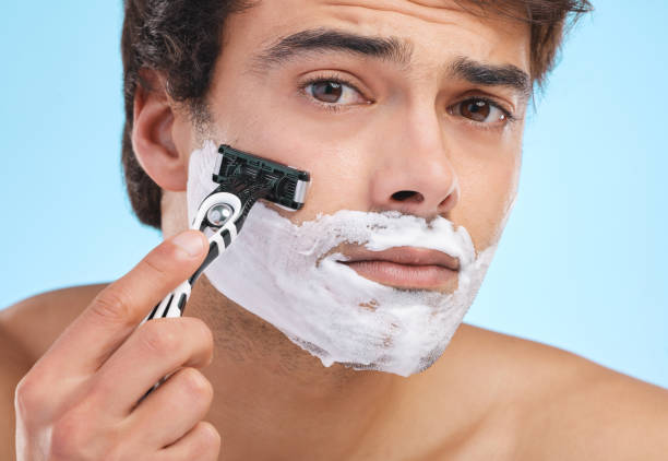 istock Shot of a young man shaving his face against a studio background 1374454563
