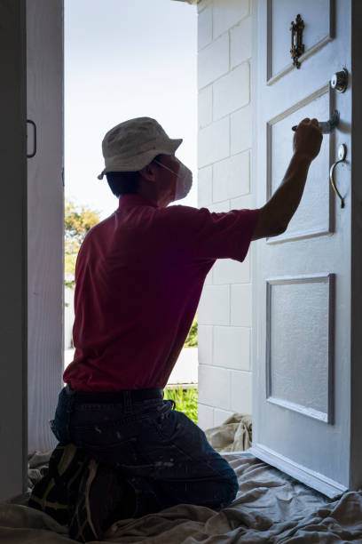 istock Man wearing facemask, painting a white door with paintbrush. Vertical format. 1374456300