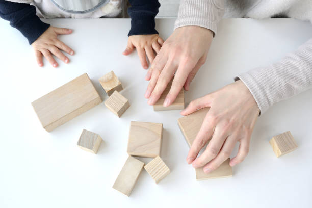 Mother and child's hands playing with wooden blocks