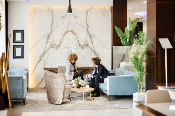 호텔 로비에 앉아 문서를 보고 검토하는 비즈니스 파트너. - business travel luxury indoors plant 뉴스 사진 이미지