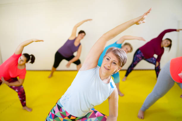 damas en una clase de ejercicios - women yoga yoga class mature adult fotografías e imágenes de stock