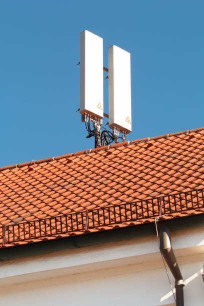 istock Cellular antenna on a rooftop with red tiles and a drainpipe against a blue sky 1374470371