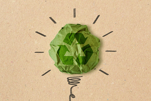 Dibujo de bombilla con cartel de reciclaje sobre papel reciclado arrugado - Concepto de ecología y reciclaje photo
