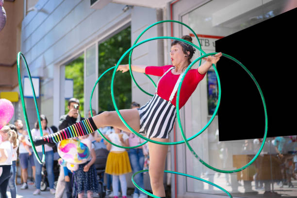A circus trouper rotating six hoops around her body Two hoops spinning on one arm, and two hoops twirling on her other arm, and a hoop whirling around each leg, this artist is showing off to an audience circus performer stock pictures, royalty-free photos & images