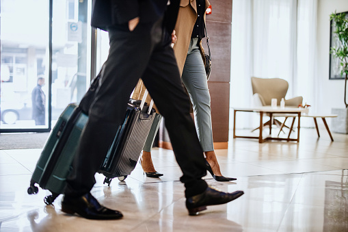Business travellers with suitcases walking towards reception