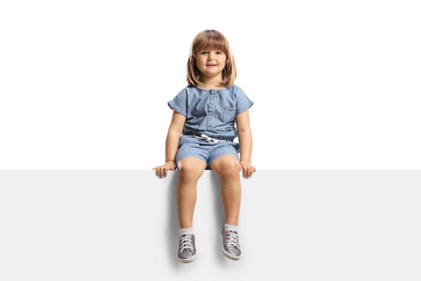 A little girl smiling and looking at the camera while holding her coin bank, symbolizing savings, financial education, and planning for future education costs. The image reflects hope, responsibility, and childhood learning about money.