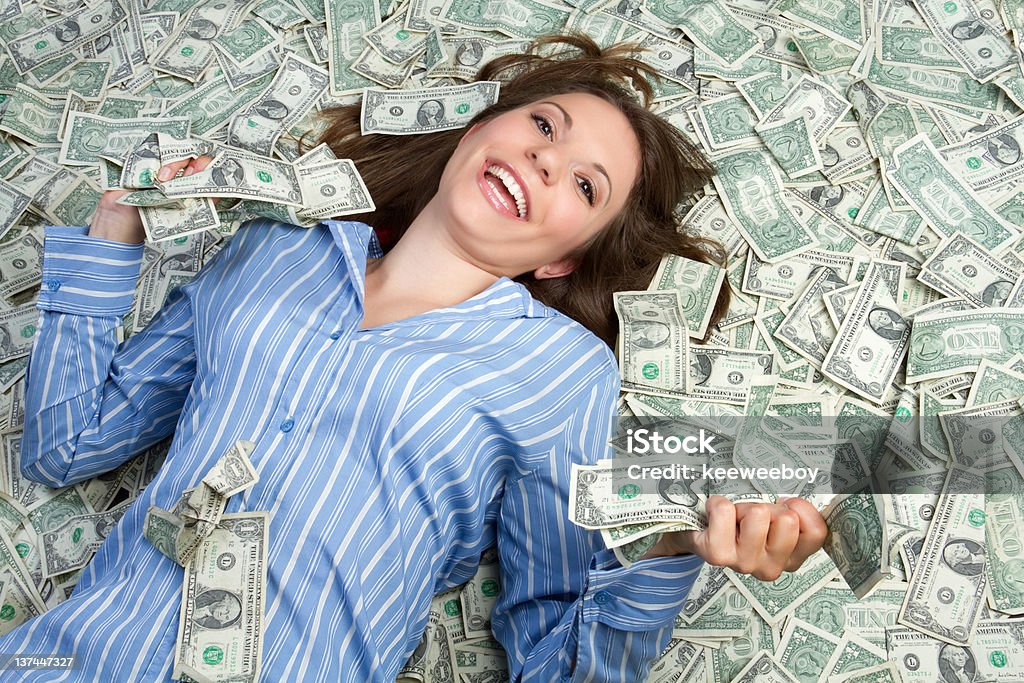 Woman in blue shirt smiling while lying in money Smiling business woman lying in money Currency Stock Photo
