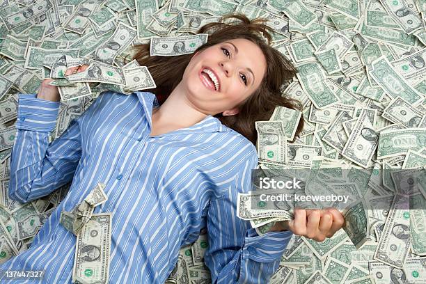 Woman In Blue Shirt Smiling While Lying In Money Stock Photo - Download Image Now - Currency, Lying Down, Heap