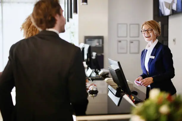 Female hotel receptionist helping a business couple guests in checking in process. Hotel receptionist assisting guests for checking in