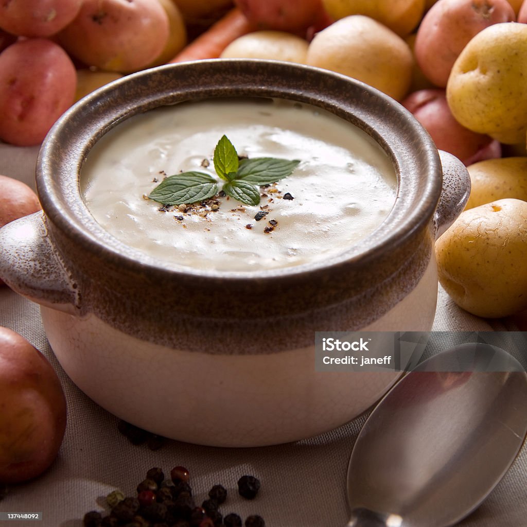 Bowl of warm creamy potato soup Fresh potato soup garnished with mint leaves, set on the table with various vegetables Potato Soup Stock Photo