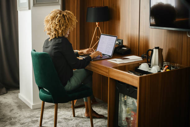 Businesswoman working on laptop in the hotel room Woman on a business trip using laptop in the hotel room to work hotel suite stock pictures, royalty-free photos & images