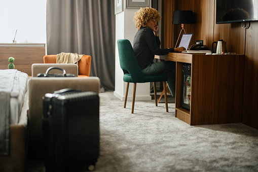 Woman on a business trip using laptop in the hotel room to work