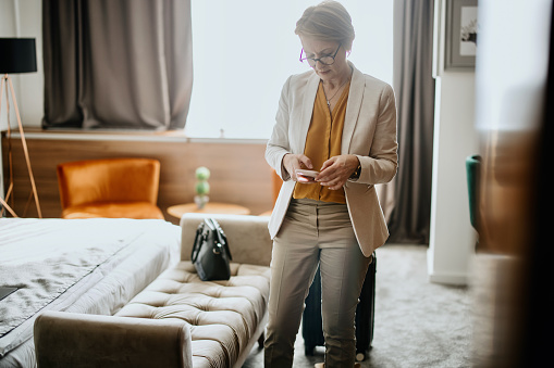 Business woman sitting in hotel room relaxing and using phone to text or talk