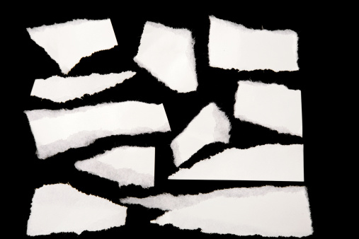 Pieces of white ripped paper on black