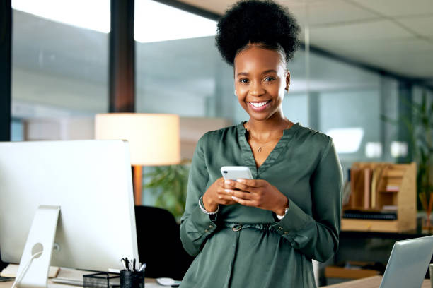 foto de una joven empresaria usando un teléfono en una oficina en el trabajo - descendencia africana fotografías e imágenes de stock