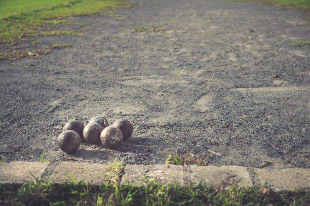 Metallic petanque balls with shooting in action on the gravel.
