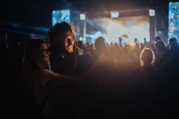 coppia che si fa un selfie con uno smartphone in un festival musicale - celebration group of people family crowd foto e immagini stock