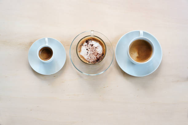 istock Three cups with various coffee, espresso, cappuccino and lungo crema on a light wooden table, copy space, high angle view from above 1374513771