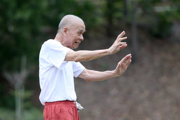 An Asian senior man is enjoying relaxation morning exercise at public park.
