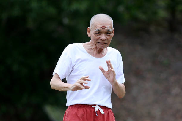 An Asian senior man is enjoying relaxation morning exercise at public park.