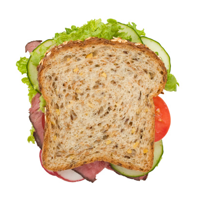 Multi-grain roast beef sandwich with lettuce, tomatoes, cucumbers and radishes, viewed from the top, with a clipping path