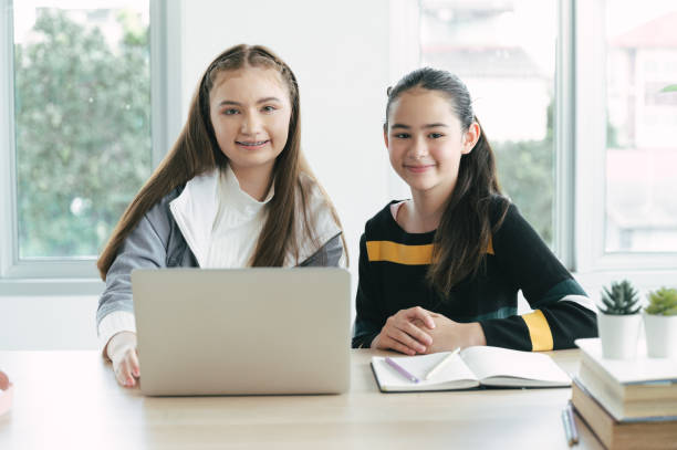 istock Girl student with friend online learning class with laptop computer and book at home 1374518367