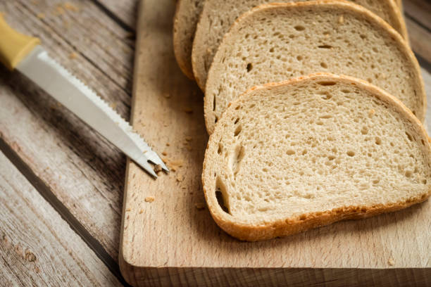 istock Sliced ​​fresh bread and a cutting knife on a rustic table 1374518416