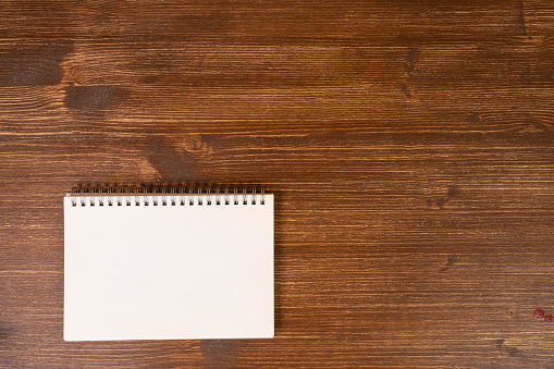 A blank notepad on a wooden background surface
