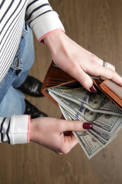 Woman counting hundred dollar bills from her wallet stock photo