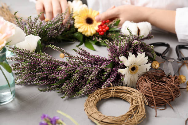 istock Florist making beautiful autumnal wreath with heather flowers at light grey table, closeup 1374525749