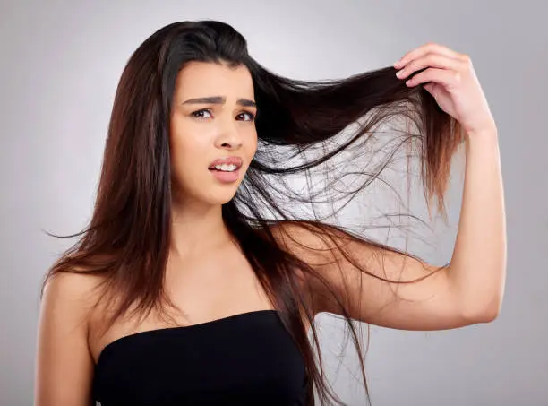 Photo of Studio portrait of an attractive young woman having a bad hair day against a grey background