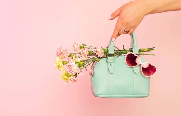 Photo of Fashion spring accessories - mint handbag (purse) and heart shaped sunglasses on pastel pink.