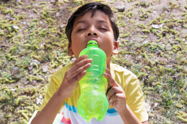 istock Young boy drinking water after yoga at park 1374561354