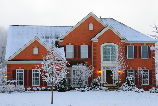 Photograph of a modern brick house after a snowfall.