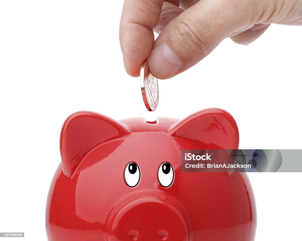 Inserting coin into a piggy bank Hand putting coin into a piggy bank Banking Stock Photo