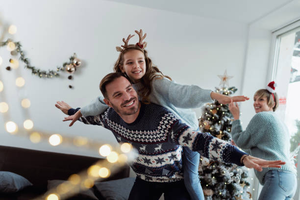 Christmas morning goofing with children Father carrying daughter piggyback on a joyous Christmas morning family christmas stock pictures, royalty-free photos & images
