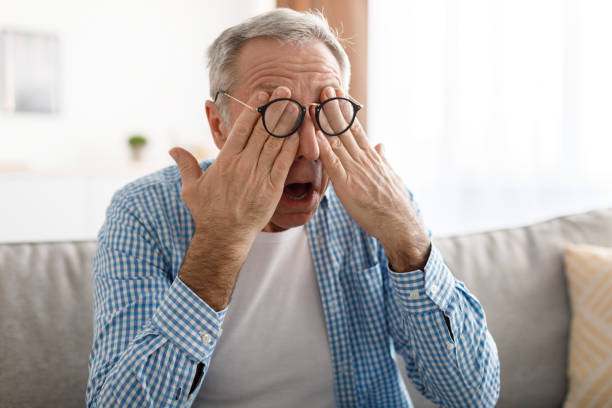glaucoma. senior man rubbing tired eyes wearing eyeglasses - macular degeneration imagens e fotografias de stock