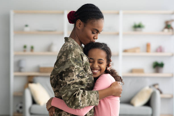 side view of black mother in military uniform hugging child - homecoming imagens e fotografias de stock