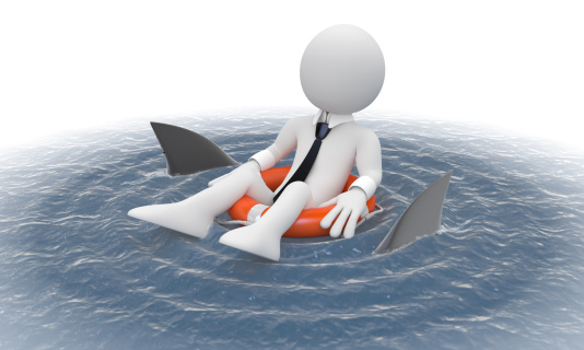 Businessman floating in a life preserver with sharks around