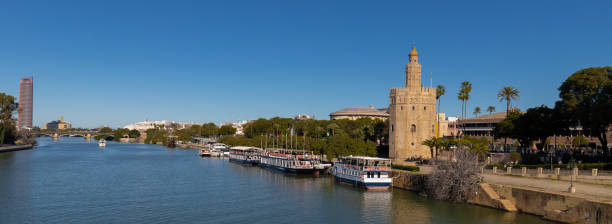 The golden tower on riverside of Guadalquivir river in downtown Seville The golden tower in the Centre of Seville alongside the river. The golden tower as it was named, is a popular spot to start a walk on the boulevard seville port stock pictures, royalty-free photos & images