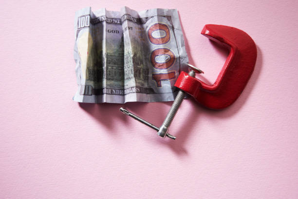 istock clamp squeezing  with dollar banknotes isolated on pink background. 1374611077