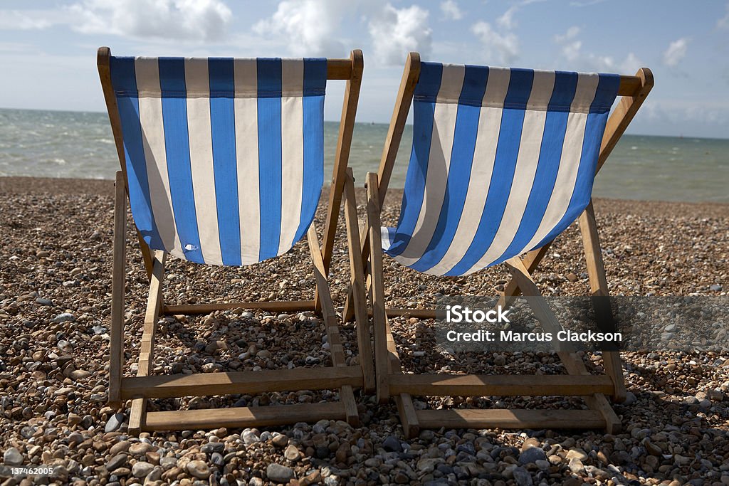 Rayado Deckchairs Pebbled en la playa - Foto de stock de Agua libre de derechos