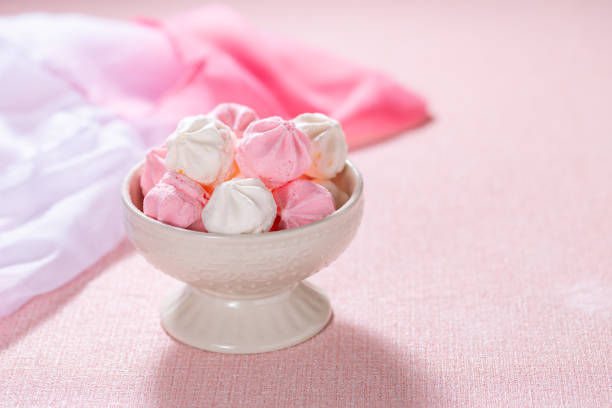 Meringue cookies on pink pastel background with copy-space.