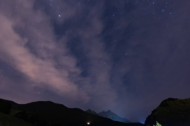 istock panoramic view over the cloudy starry blue sky from under the mountains at night 1374673655