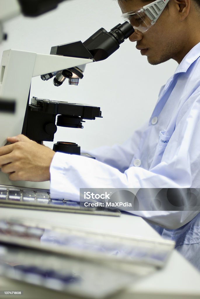 Hombre científico mirando a través de un microscopio con borrosa plano - Foto de stock de Asistencia sanitaria y medicina libre de derechos