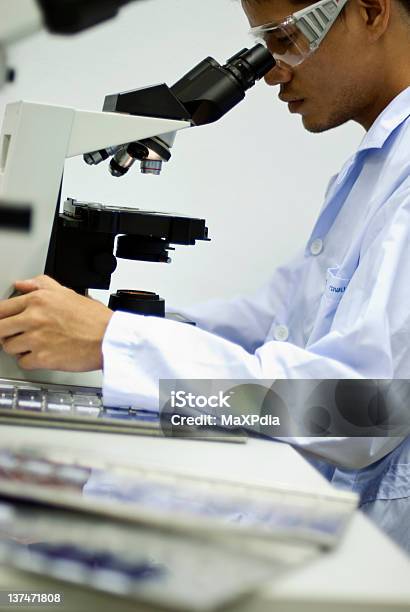 Hombre Científico Mirando A Través De Un Microscopio Con Borrosa Plano Foto de stock y más banco de imágenes de Asistencia sanitaria y medicina