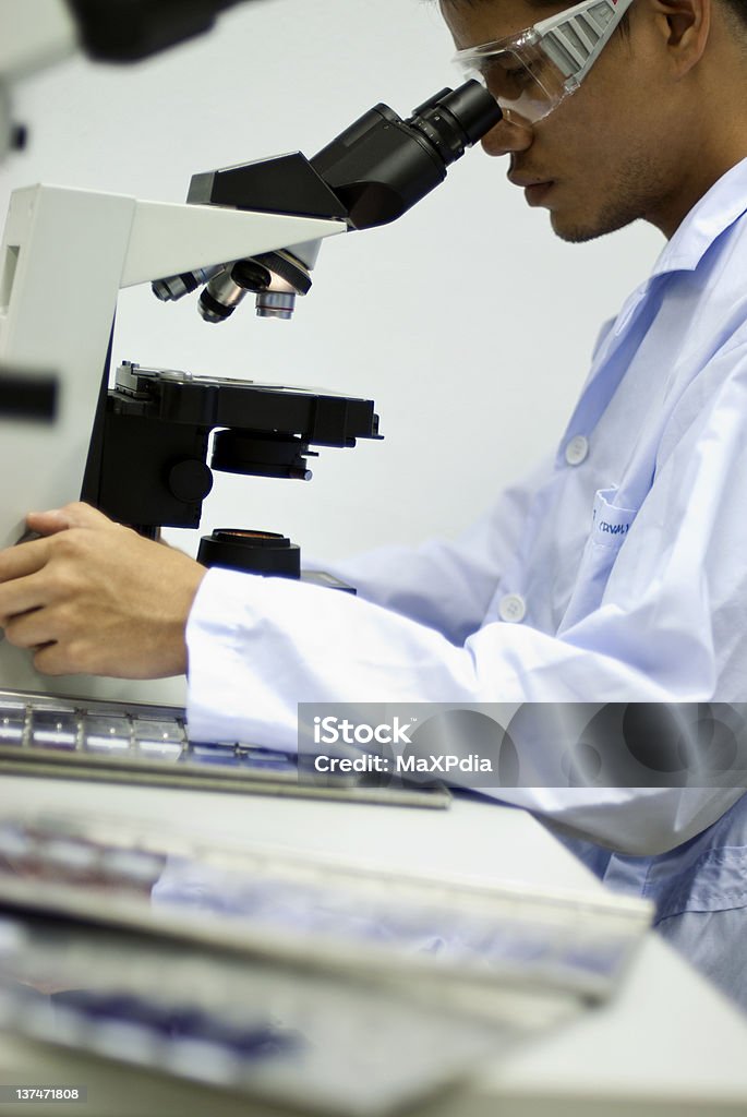 Masculino cientista olhando pelo microscópio com fundo desfocado - Foto de stock de Cientista royalty-free