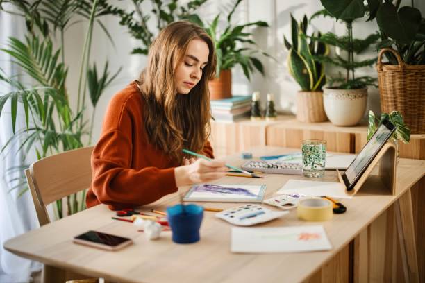 istock Young woman using different techniques to watercolour painting at home 1374727259
