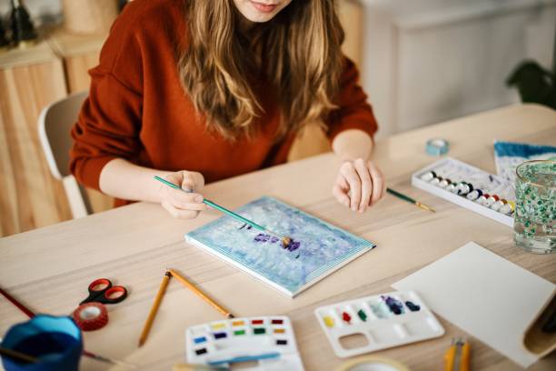 istock Young woman using different techniques to watercolour painting at home 1374727798