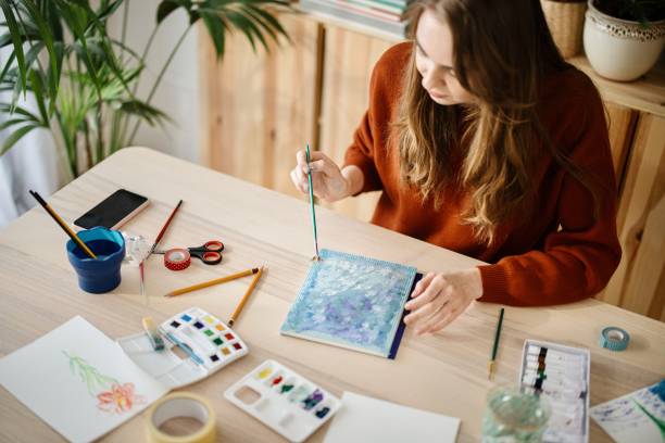 istock Young woman using different techniques to watercolour painting at home 1374727802